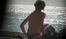 金发裸体主义者在海滩上脱衣服