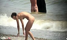 O tipă nud cu părul negru se plimbă goală pe o plajă